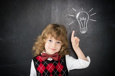 smart kid in class. happy child against blackboard. drawing light bulb. idea concept