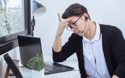 asian adult and handsome man wearing headphone, getting stress and headache while using microphone and laptop to work and do online meeting. new normal, social media, health and technology concept.