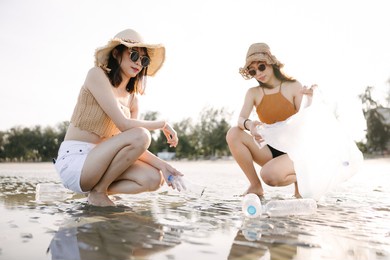 young womens cleaning beach area. volunteer collecting trash on the beach. ecology concept. 