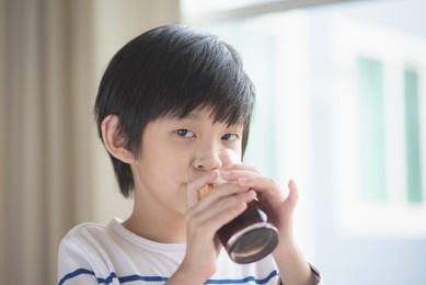 little asian boy drinking soft drink cola soda