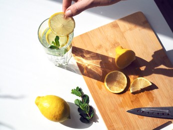 woman preparing lemon water. detox water with mint and lemon. refreshing summer drink. wellness, diet, healthy eating concept