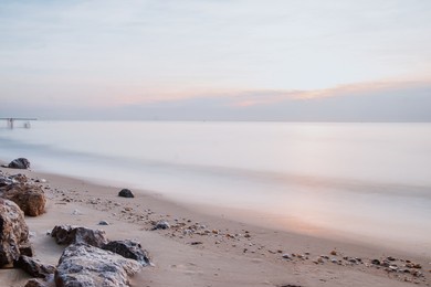 long exposure sea rocks magnificent sunrise view at sunrise romantic atmosphere in peaceful morning at sea. pink horizon with first hot sun rays.
