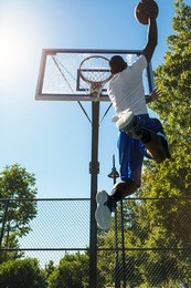 young basketball player drives to the hoop with a high flying slam dunk. slight lens flare.