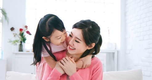 asian child hug her mom from back and smile happily
