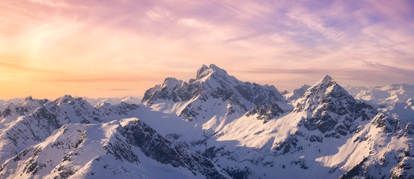 aerial view from airplane of blue snow covered canadian mountain landscape in winter. colorful pink sky art render. tantalus range near squamish, north of vancouver, british columbia, canada.