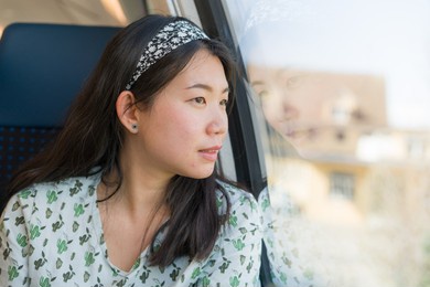 train travel getaway - lifestyle portrait of young happy and beautiful asian korean woman traveling on railway looking through window 