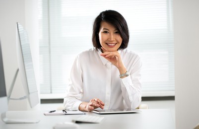 asian business woman smiling at camera at workplace in an office