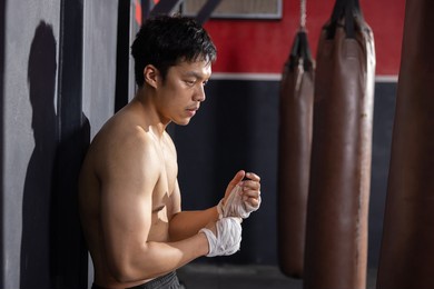 asian boxer wrapping his hands before thai boxing training