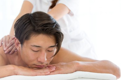 an asian man is getting a back massage.