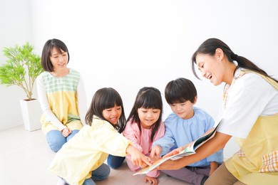 nursery teacher and children reading a picture book