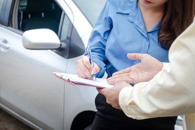 a woman driving a car has an accident during the rain. signing the auto insurance claim document with an insurance agent. concept a road traffic
