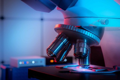 toned photo of a backlit microscope lens in a science laboratory