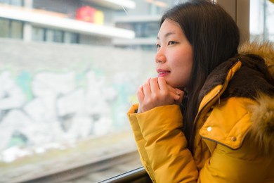 young beautiful and happy asian korean woman sitting on train looking out to window enjoying holidays travel in europe smiling thoughtful and sweet