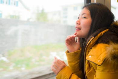 young beautiful and happy asian japanese woman sitting on train looking out to window enjoying holidays travel in europe smiling thoughtful and sweet