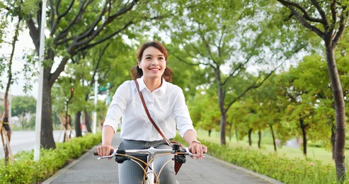 asian businesswoman commute by bicycle through the city happily
