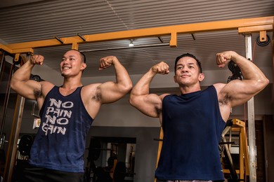 two friends enjoy a friendly posedown after training, doing double bicep poses. having fun and camaraderie at the gym.