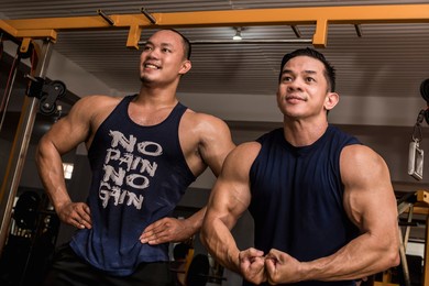 two friends enjoy a friendly posedown after training, doing standing relaxed and most muscular poses. having fun and camaraderie at the gym.