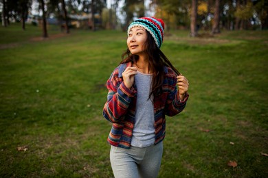 cute asian teen girl walking in autumn forest. portrait of candid woman in hat enjoying autumn in the forest .