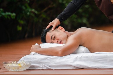 asian man enjoy a massage by the resort's pool. 
