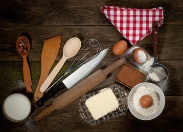 baking cake in rural kitchen - dough recipe ingredients (eggs, flour, milk, butter, sugar) and rolling pin on vintage wood table from above. rustic background with free text space.