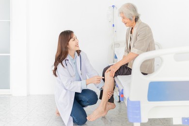 smart asian female doctor holding leg of old stroke patient in hospital, elderly rehabilitation clinic, they training to rehab muscle
