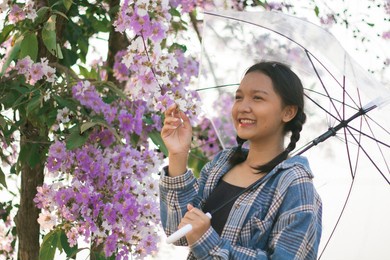 asian young girl hold umbrella with purple flower.