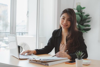 happy business woman executives discussing financial reports and using laptop in modern bright office indoor.