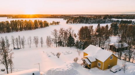 aerial view from drone of frozen lake covered by white snow near small cozy village with colorful houses on north, bird’s eye view of lapland countryside land with scenery environment 
