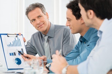 portrait of mature businessman showing annual report graph to his colleague