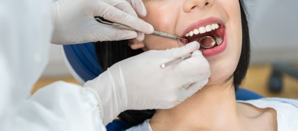 close up of caucasian beautiful young girl patient's teeth open mouthed to receive treatment from expert dentist doctor for oral check up and examining cavities disease for tooth care at dental clinic