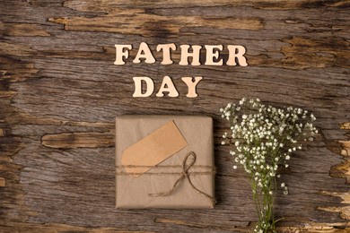gift box in brown paper with the inscription with wooden letters father's day on a wooden background. flat lay. father's day gift for dad. father's day holiday concept in 2021