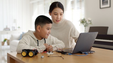 young asia student remotely learn online at home with parent in coding robot car and electronic board cable in stem, steam, mathematics engineer science technology computer code in robotics for kids.