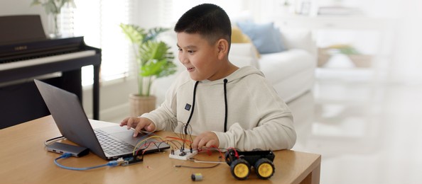young asia student remotely learn online at home in coding robot car and electronic board cable in stem, steam, mathematics engineering science technology computer code in robotics for kids concept.