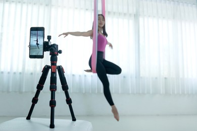 asian beautiful woman doing aerial dance in hammock and broadcast her class live online and recording by smartphone from studio, asian women perform dances using a hammock in the dance