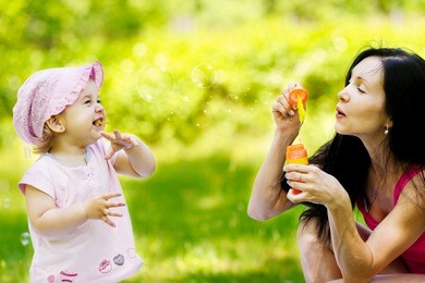 mother playing with her little daughter blowing bubbles
