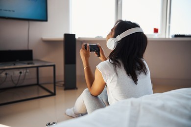 young woman in headphones playing video game at home