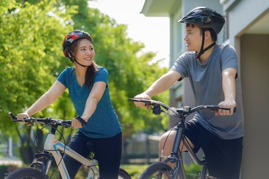 asian couple wearing a helmet while preparing for a bike ride around her neighborhood for daily health and well being, both physical and mental.