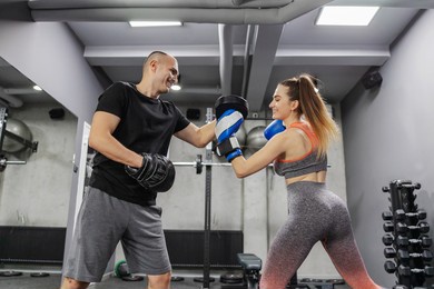 boxing training class. lady wears boxing gloves and hits the protection that the trainer wears in the gym. using a boxing glove with a partner. close-up of movement and energy in kickboxing training