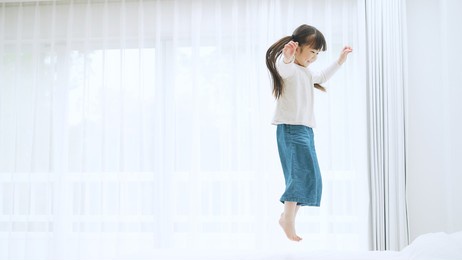 asian little girl playing on a bed.