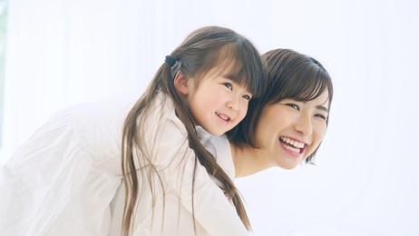 young asian woman piggybacking a little girl.