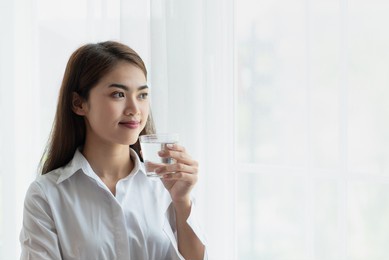 portrait of young asian woman holding glass of water