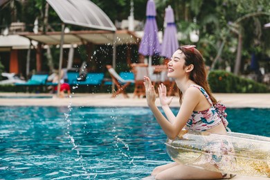 happy traveler asian woman with bikini and pool float relax beside swimming pool in luxury resort at thailand, summer travel vacation concept