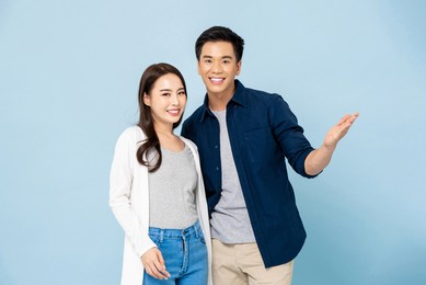 lovely young happy smiling asian couple in casual clothes on light blue isolated studio background