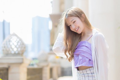 asian beautiful lady who has bronze hair smiles and walks on the street in fashion style theme.