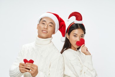 cheerful young couple of asian appearance with hearts in hands holiday christmas