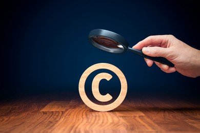 focus on copyright and intellectual property concept. hand with magnifying glass focused on copyright symbol.