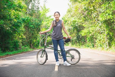women are cycling road bike in the morning.she is on a forest road. healthy lifestyle - people riding bicycles in city park. urban biking - woman riding bike in natural road.