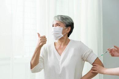 
woman with gray hair bravely accepts injection