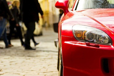 fragment of red sport car with headlight in sunlight at sunset