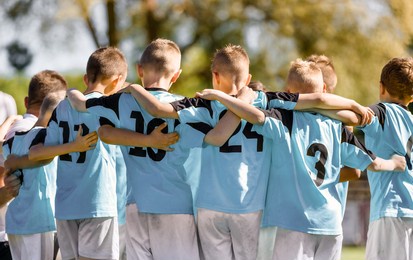 kids team members in sport team. happy boys huddling in football team. children standing in a circle together. kids motivational speech before the match